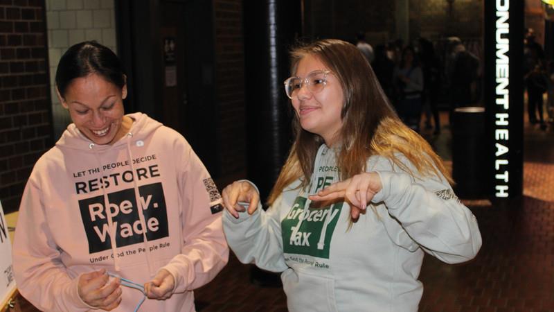 Activists wearing “restore Roe v. Wade” and “Repeal grocery tax” sweatshirts. 