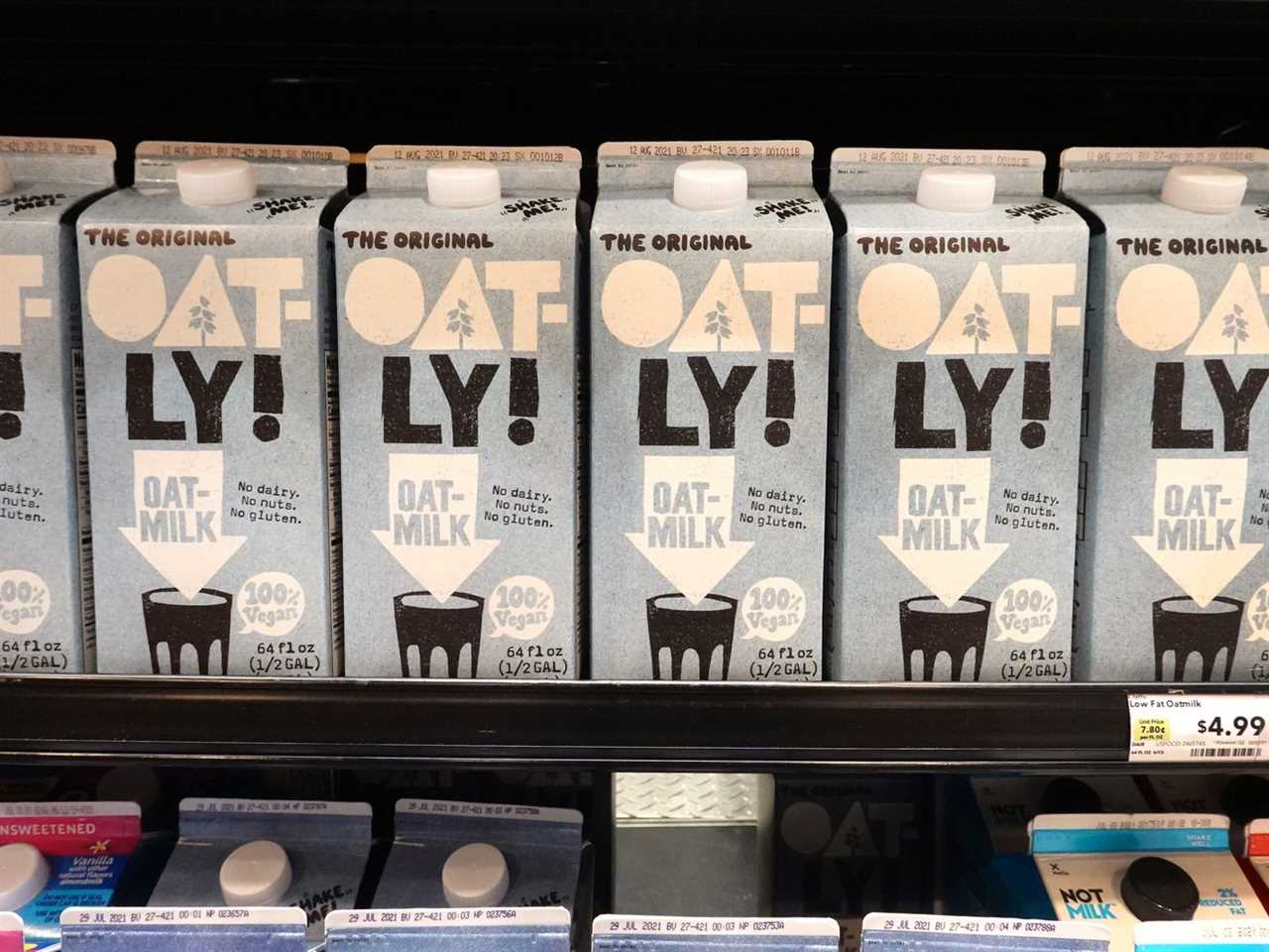 Cartons of oat milk on a refrigerator case’s shelf.