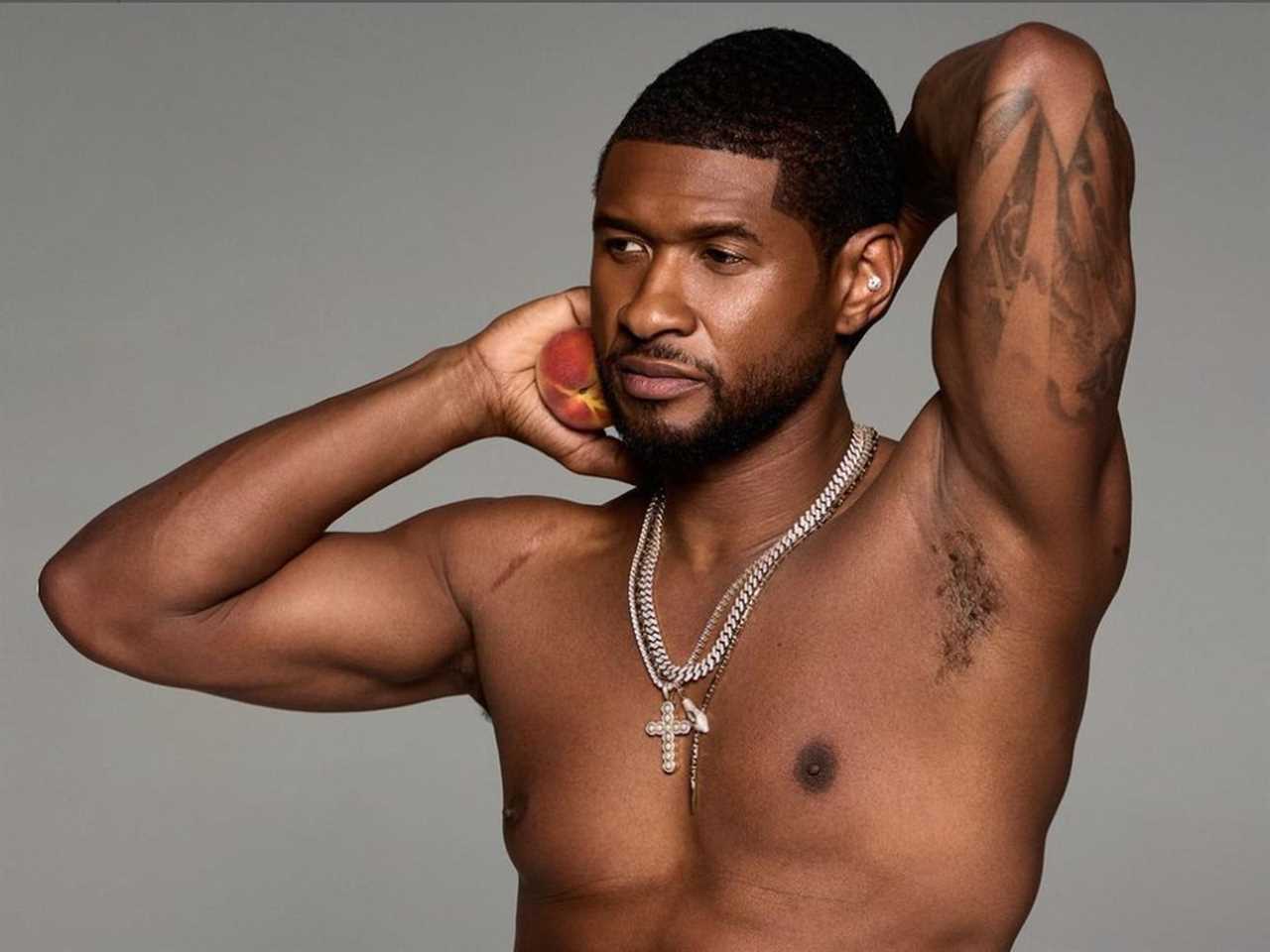 Usher posing shirtless with his arms behind his head, holding a peach.