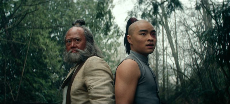 Iroh and Zuko stand back to back in a forest.